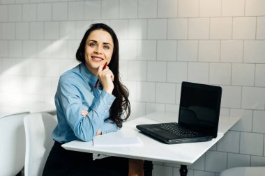 Kız ofiste dizüstü gülümseyen masada oturuyor