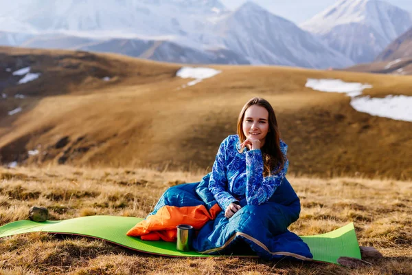 Mutlu kadın turist yüksek dağlar bir arka plan üzerinde oturur — Stok fotoğraf