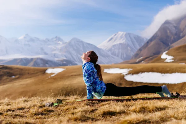 Женщина турист делает упражнения на фоне высоких гор — стоковое фото