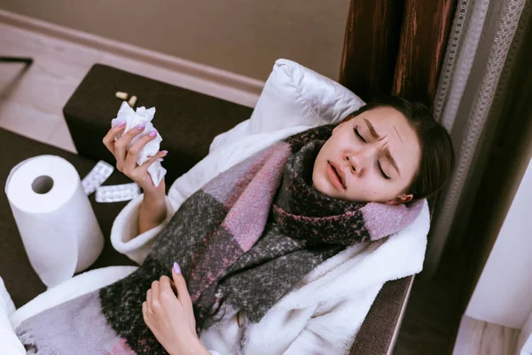 O femeie bolnavă cu o eșarfă caldă se află pe pat — Fotografie, imagine de stoc