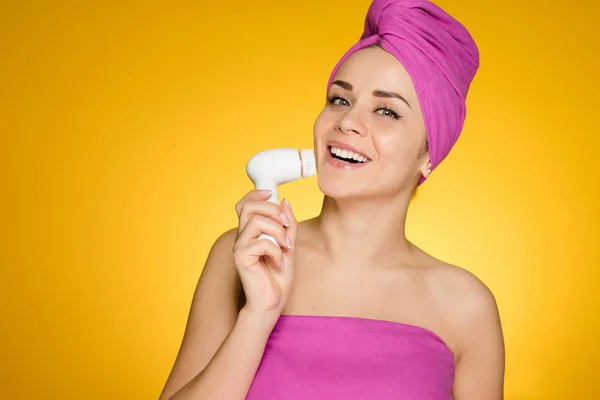 Kvinna med en handduk på huvudet borsta hennes ansikte med en borste för djuprengöring — Stockfoto