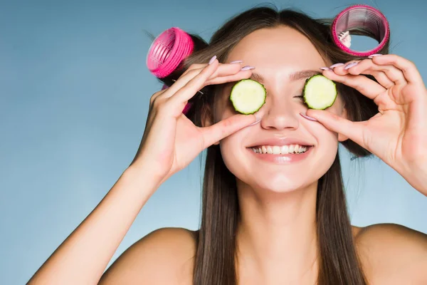 Curlers salatalık gözler yakın tutarak başında mutlu kadınla — Stok fotoğraf