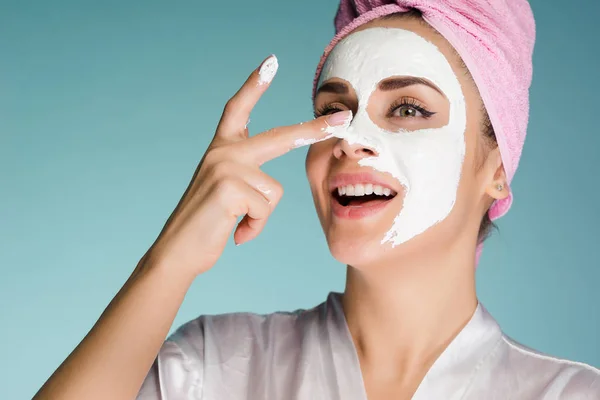 Mulher feliz com uma toalha do que em sua cabeça aplicar uma máscara de limpeza em seu rosto — Fotografia de Stock