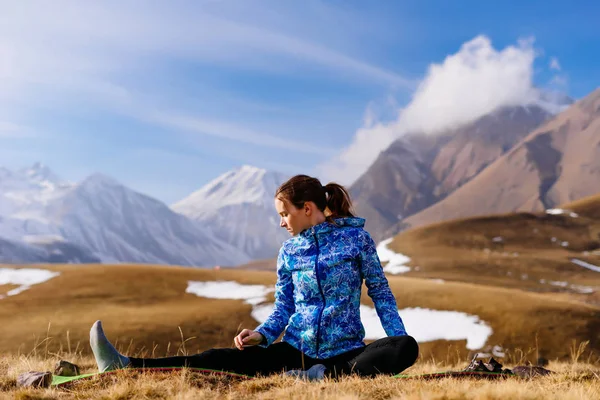 Женщина турист делает упражнения на фоне гор — стоковое фото