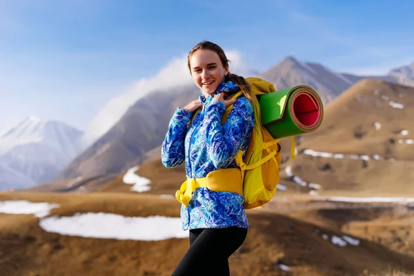 Mujer feliz turista con una mochila sobre un fondo de montañas —  Fotos de Stock