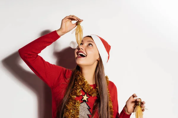 Glückliche Frau im Neujahrsanzug auf weißem Grund hält ein Neujahrsspielzeug in der Hand — Stockfoto