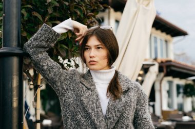 esmer genç şehir kızı gri paltolu bir şey hakkında düşünüyor şehrin sokaklarında yürüyor