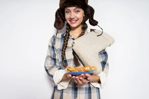 幸せな美しいロシアの女の子より吹返しと暖かい帽子でカーニバルを祝う、ホットケーキを保持 — ストック写真