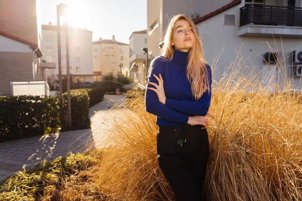 Menina modelo loira elegante em suéter azul posando, andando ao ar livre ao sol — Fotografia de Stock