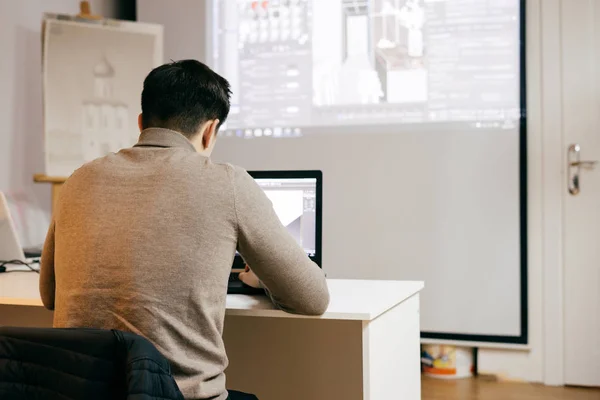 Мужчина работник, графический дизайнер, работает над проектом на ноутбуке, в офисе — стоковое фото
