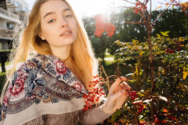 Hermosa joven rubia en una hermosa bufanda caminando por el jardín al sol, disfrutando de la naturaleza — Foto de Stock