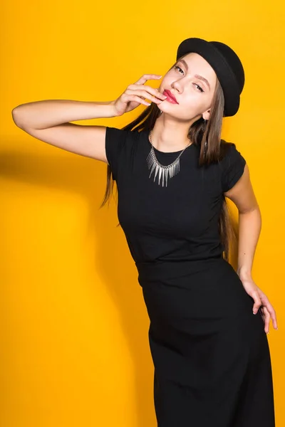 Menina elegante atraente em um vestido preto e um chapéu preto na moda posando, no pescoço um colar caro — Fotografia de Stock