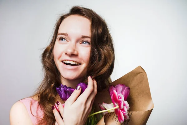 Mesafe içine bakarak, büyük bir buket çiçek holding, anneler günü kutlama ve gülüyor güzel mavi gözlü genç kadın — Stok fotoğraf