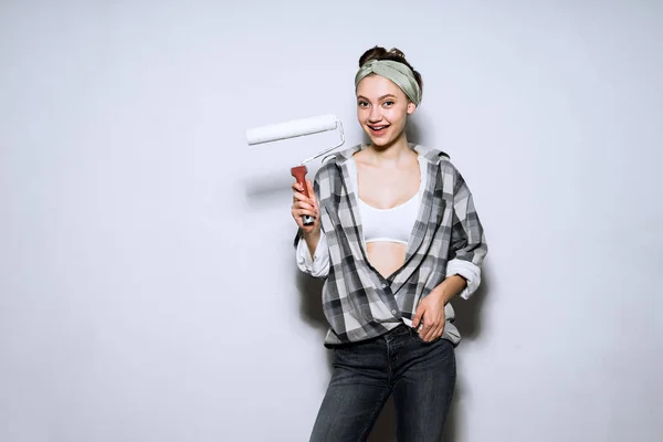Милая красивая девушка художник держит в ручной ролик для покраски стен, делает ремонт — стоковое фото