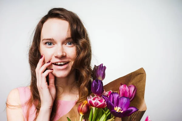 Felice bella ragazza dagli occhi azzurri sorridente, che tiene un grande mazzo di fiori, celebrando la giornata mondiale della donna, 8 marzo — Foto Stock