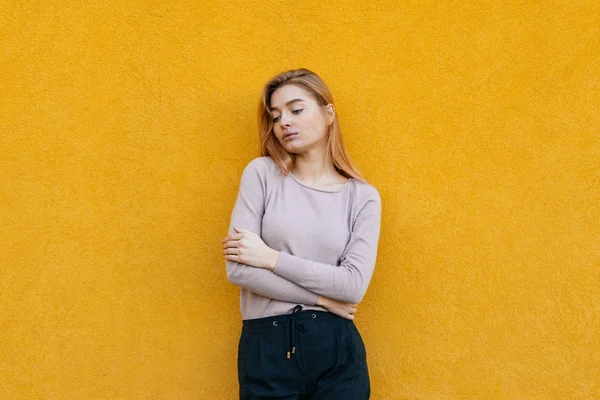 Linda chica rubia joven en ropa de moda posando contra la pared amarilla, estilo de calle — Foto de Stock