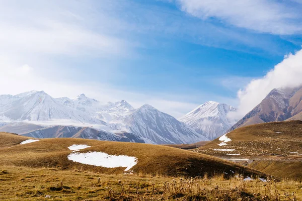A varázslatos természet és a táj, a kaukázusi magas hegyek borítják fehér hó, a kék ég, a határtalan sárga mezők — Stock Fotó
