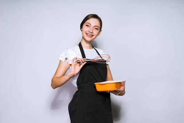 Щаслива красива дівчина шеф-кухаря в чорному фартусі готує смачну страву, торт — стокове фото