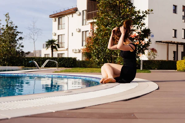 Una ragazza attraente di lusso gode di una ricca vita e tempo libero, si siede a bordo piscina — Foto Stock