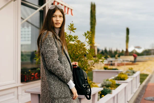 Élégante fille de la ville aux cheveux bruns dans les promenades manteau gris, en plein air, style de rue et de la mode — Photo