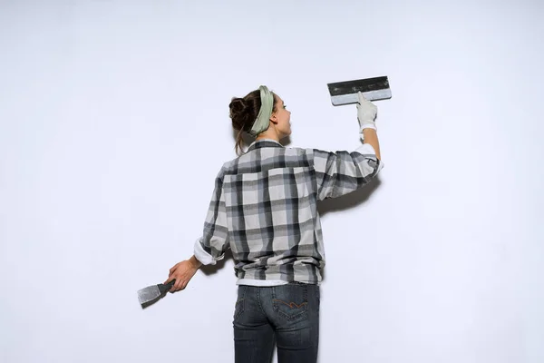 Construtor menina, pintor, em uma camisa xadrez, as paredes são niveladas com uma espátula, um reot no apartamento — Fotografia de Stock