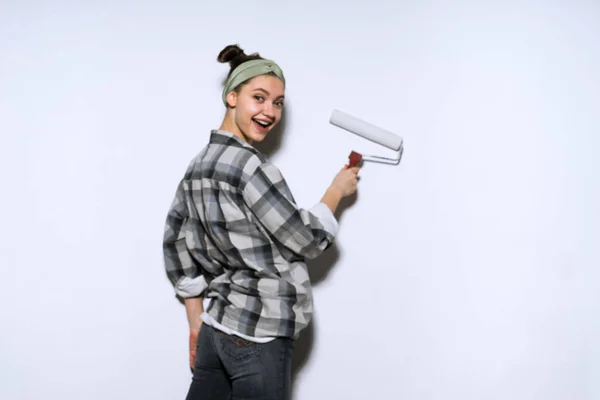 Feliz joven pintora pinta la pared con un rodillo en blanco — Foto de Stock