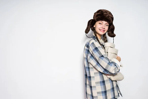 Fröhliches junges Mädchen aus Russland mit warmer Pelzmütze bereitet sich auf einen kalten Winter vor, hält graue Filzstiefel in der Hand — Stockfoto