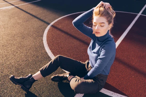Stílusos magabiztos fiatal szőke modell lány ül a játszótéren, a padlón, a tavaszi napsugarak — Stock Fotó