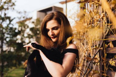 siyah bir kedi onun kollarında tutan onun Bahçe etrafında yürüyüş güzel uzun saçlı çekici kadın