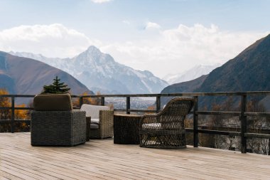 verandada olan bir masa ve sandalyeler, mavi gökyüzünün altında görkemli Dağları bir görünüm