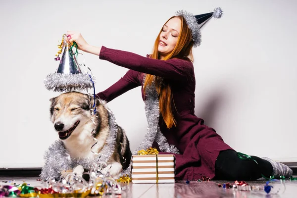 Heureuse fille aux cheveux roux s'assoit sur le sol avec son gros chien, célèbre la nouvelle année et Noël — Photo