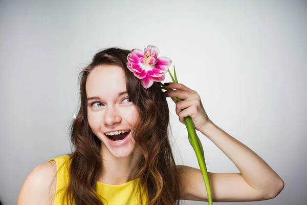 Gelukkig lachen meisje in gele jurk houdt een bloem, viert Moederdag — Stockfoto