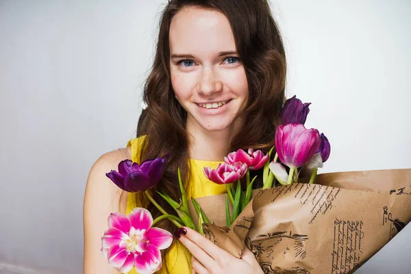 Felice bella giovane donna che tiene un mazzo di fiori profumati, celebrando la festa della mamma, sorridendo — Foto Stock