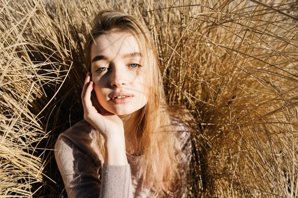 Young confident blue-eyed girl blond model posing in the field, dry grass, in the sun — Stock Photo, Image