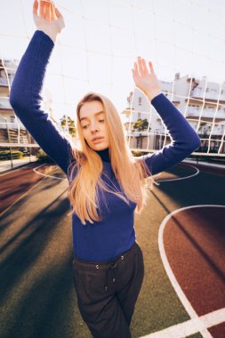 genç güzel sarışın model kız mavi kazaklı kılavuz spor sahasının poz