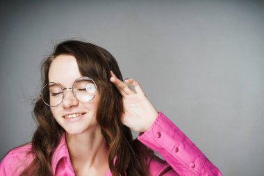 mutlu pembe gömlek ve gözlük gülümseyen kız ofis çalışanı için bir şey dinler