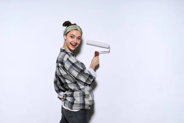 Jovem pintor feliz na camisa xadrez cor rolo de pintura em branco, reparação — Fotografia de Stock