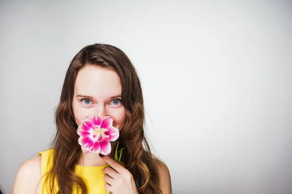 Söt vacker blåögda flicka sniffa en rosa blomma, väntar på internationella kvinnodagen — Stockfoto