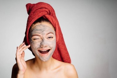 başında kırmızı bir havlu ile garip bir mutlu genç kız onun yüzüne yararlı kil maskesi uygulanmış