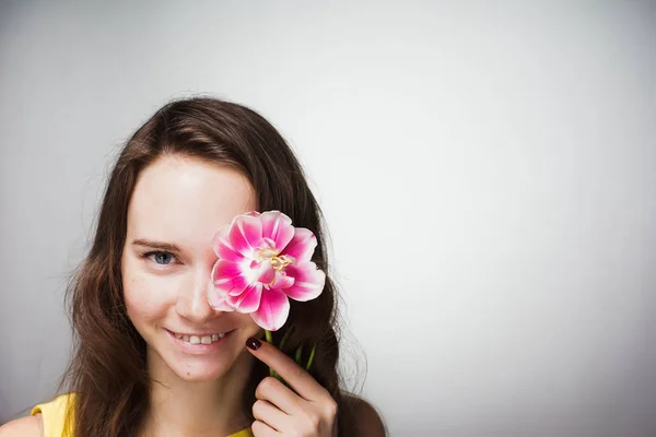 smiling beautiful young woman holding a pink flower, celebrating Mother's Day