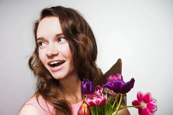 Glad vacker ung kvinna som firar en internationella kvinnodagen, gav en bukett blommor — Stockfoto