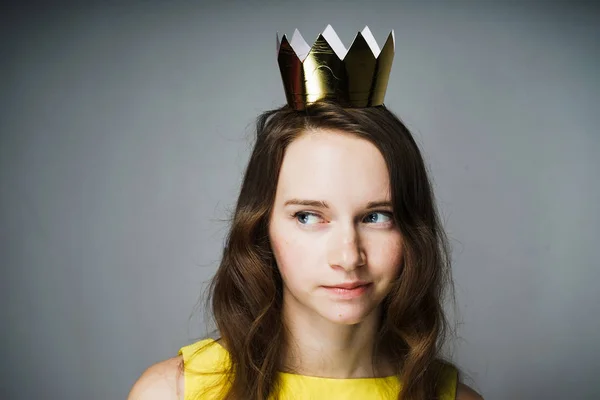 Bonito jovem mulher em um vestido amarelo, vestindo uma coroa de ouro, à espera do Dia das Mães — Fotografia de Stock