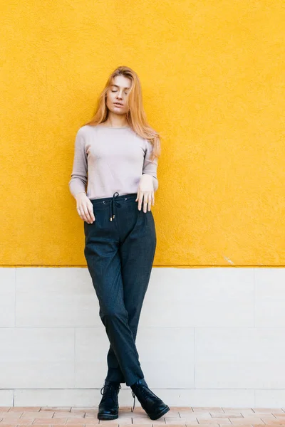 Moda jovem loira modelo menina posando contra um fundo de parede amarelo, estilo de rua — Fotografia de Stock