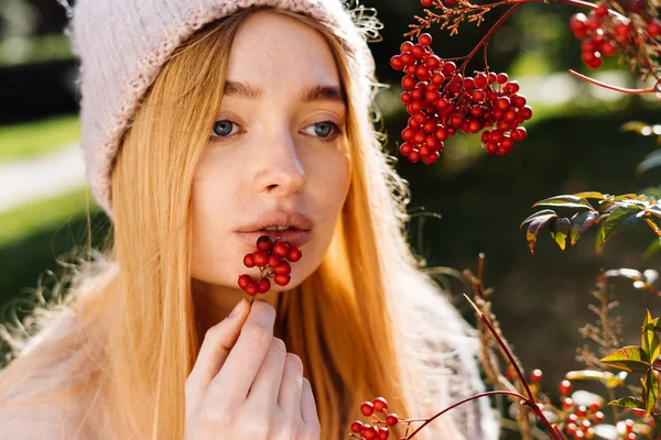 Unga vackra blåögda flicka blondin i en rosa hatt promenader i trädgården, hålla bär — Stockfoto