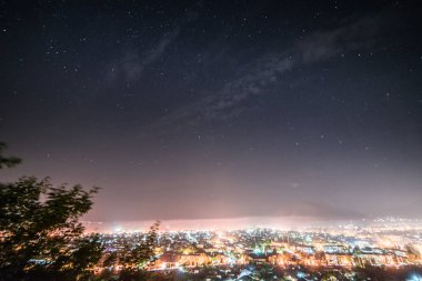 büyük bir parlak parlayan şehir, birçok fener ve ışıklar, gece yıldızlı gökyüzü altında