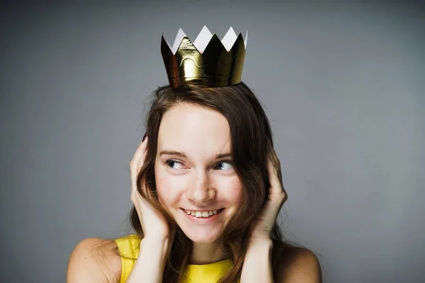 Joven feliz en un vestido amarillo cerró sus oídos, sonriendo, en su cabeza una corona de oro —  Fotos de Stock