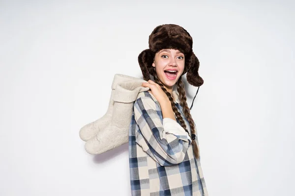 Glücklich lachendes junges Mädchen aus Russland mit Pelzmütze hält graue Winterstiefel — Stockfoto