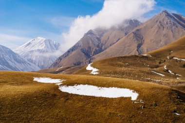 görkemli büyülü doğa, beyaz kar ile kaplı yüksek Dağları mavi gökyüzünün altında sonsuz sarı meadows