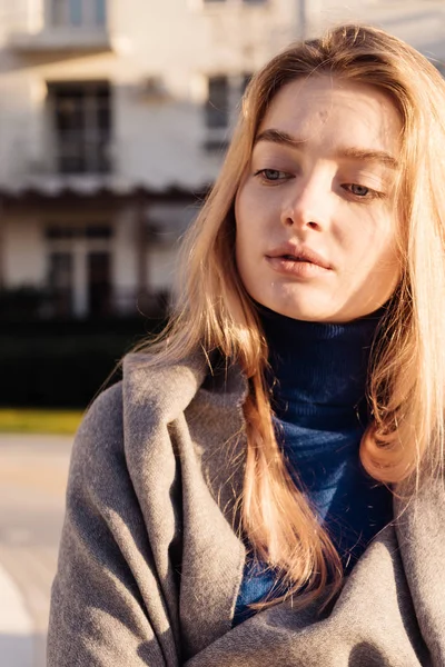 Beautiful young blond girl in a blue sweater enjoying the sun and warm spring weather — Stock Photo, Image