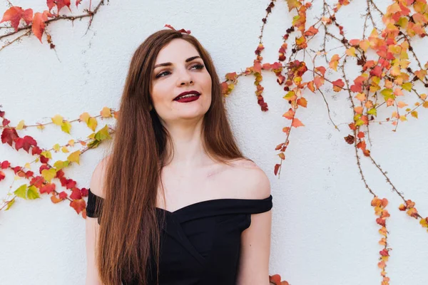 Attractive long-haired girl in black dress smiling, posing — Stock Photo, Image